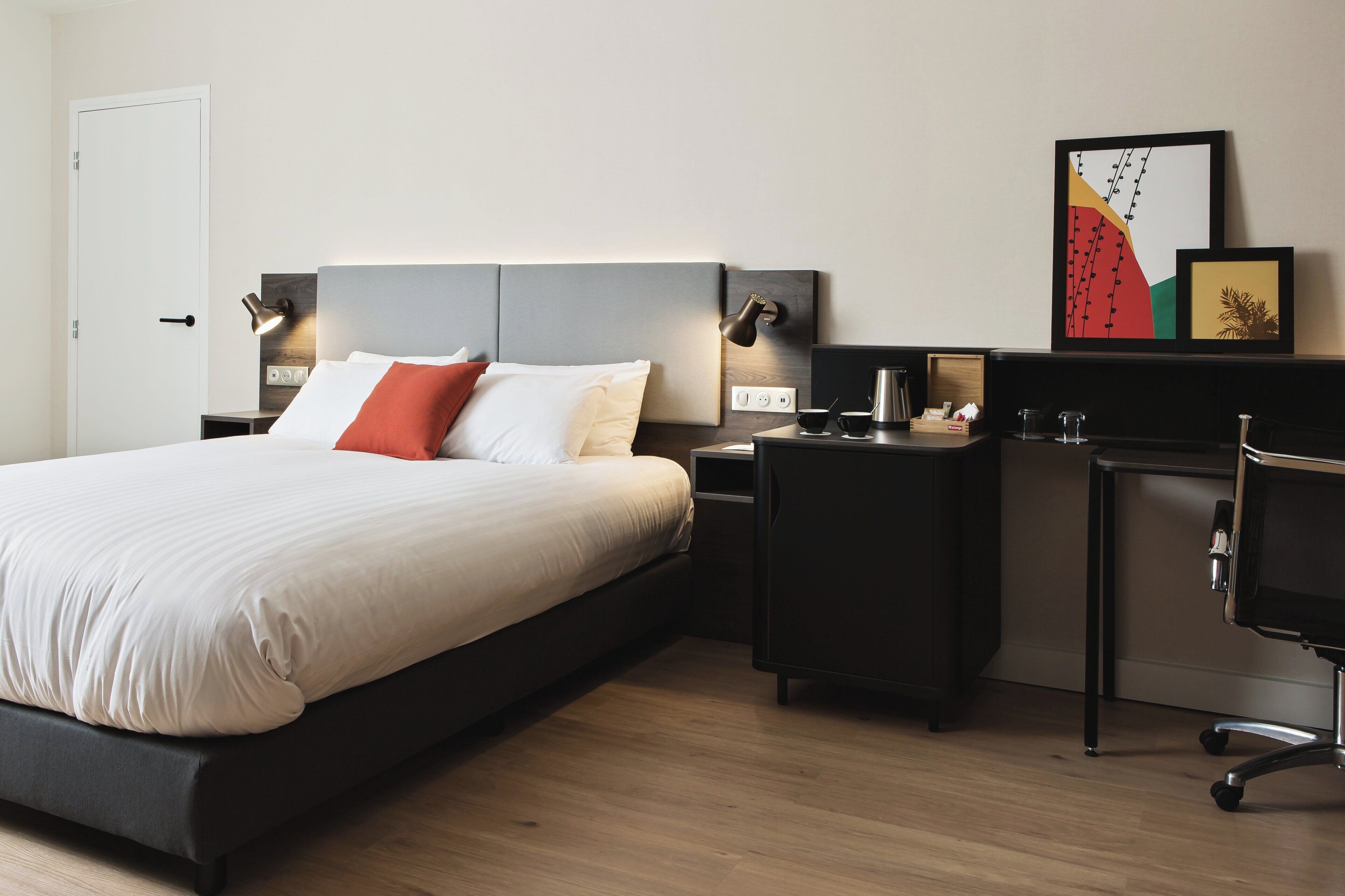 Una habitación de hotel moderna con una cama grande, mesitas de noche, un escritorio y una silla.