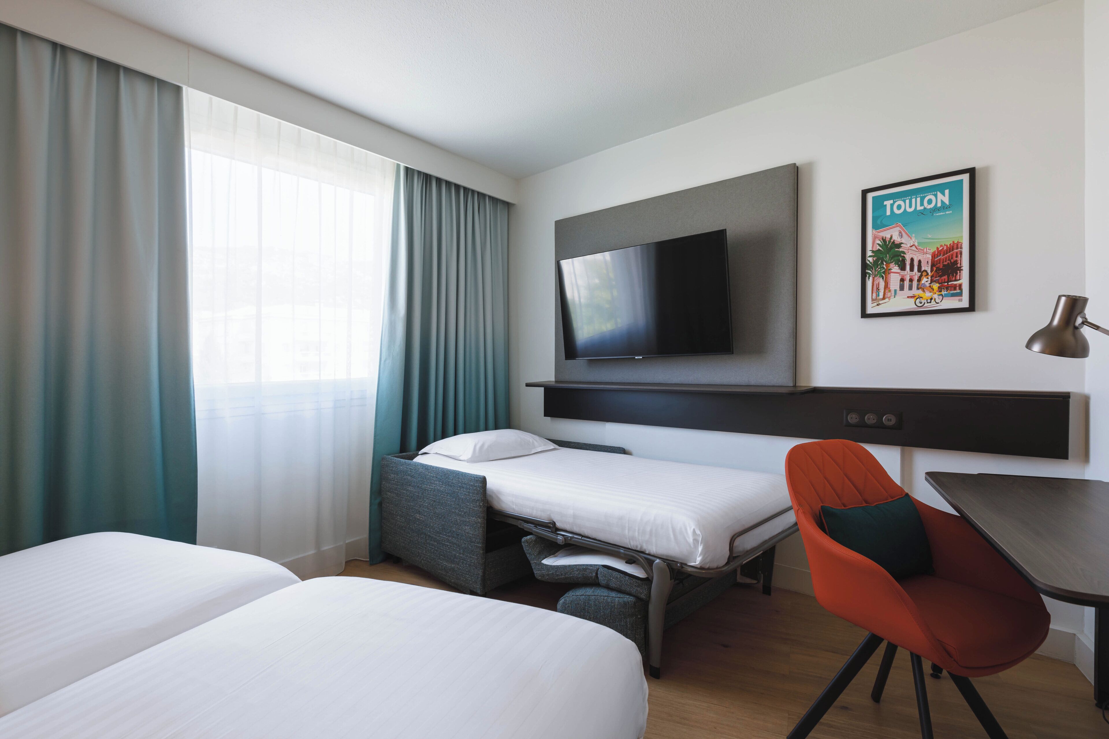 Une chambre d’hôtel avec deux lits, un téléviseur fixé au mur, un bureau et une chaise.