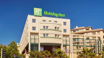 A Holiday Inn hotel with a prominent green logo, multiple balconies, and a modern facade.