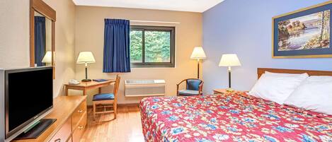 A hotel room with a bed, a desk, a chair, a TV, and a window with curtains.