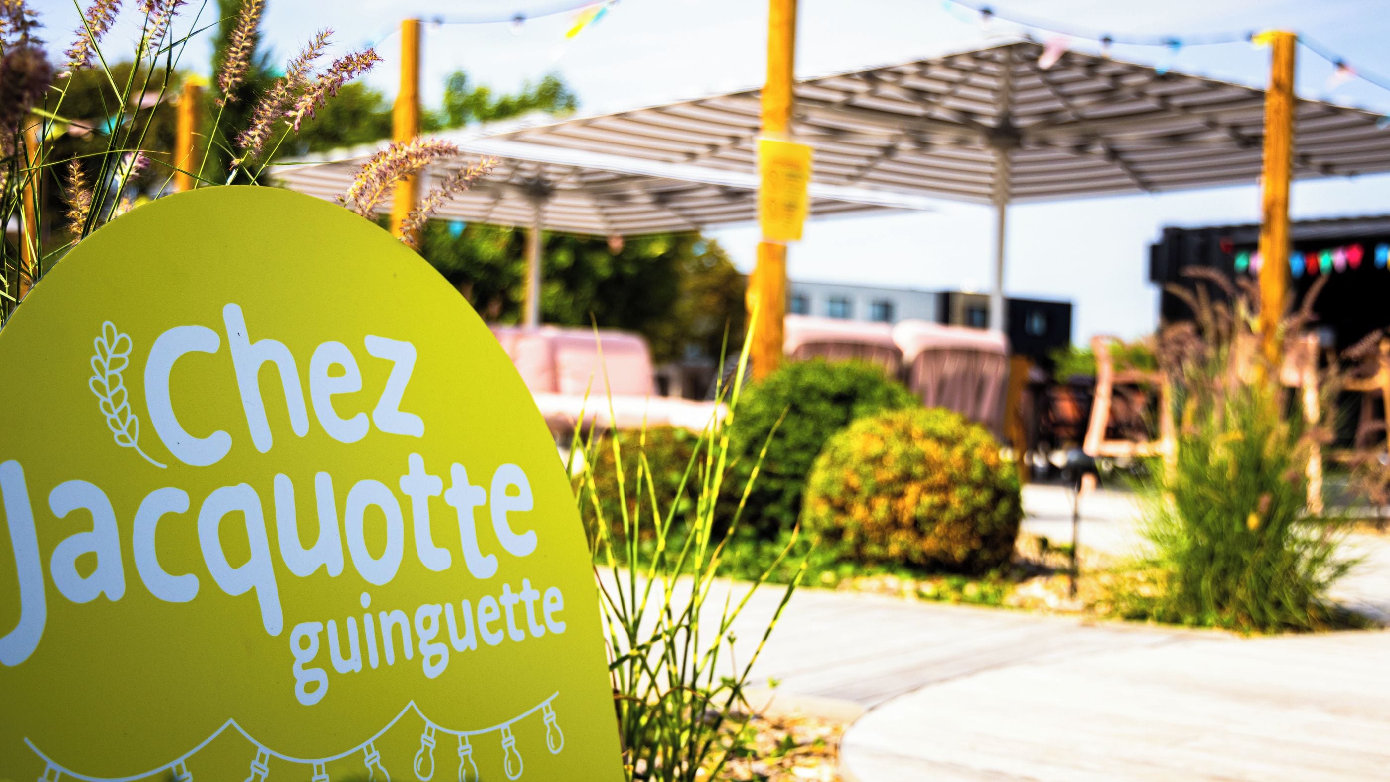 Cartel de la guinguette Chez Jacquotte mostrando claramente la terraza al aire libre y una estructura de pérgola.