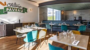 Interior de un restaurante con mesas, sillas y un letrero en la pared que dice 'le Champ PAVEAU'.