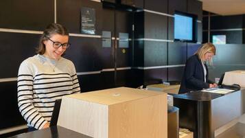 A reception desk with a wooden counter and a digital screen in the background.