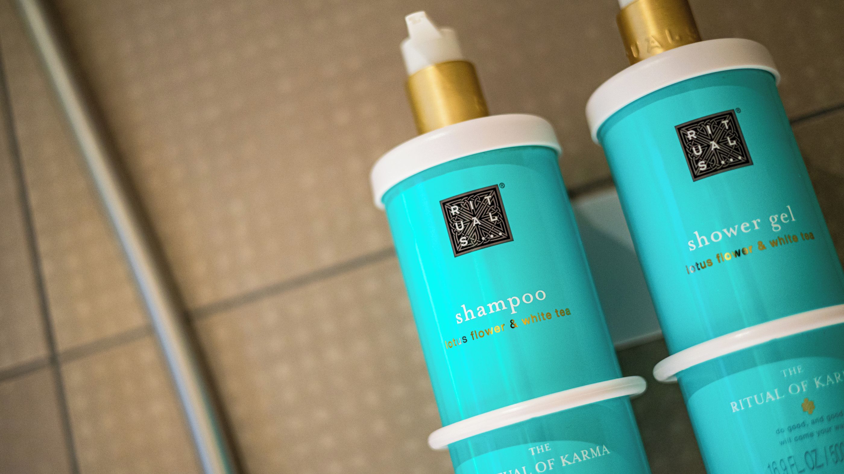 Two bottles of 'Ritual' brand shower gel with labels indicating 'shampoo lotus flower & white tea' and 'shower gel lotus flower & white tea.'