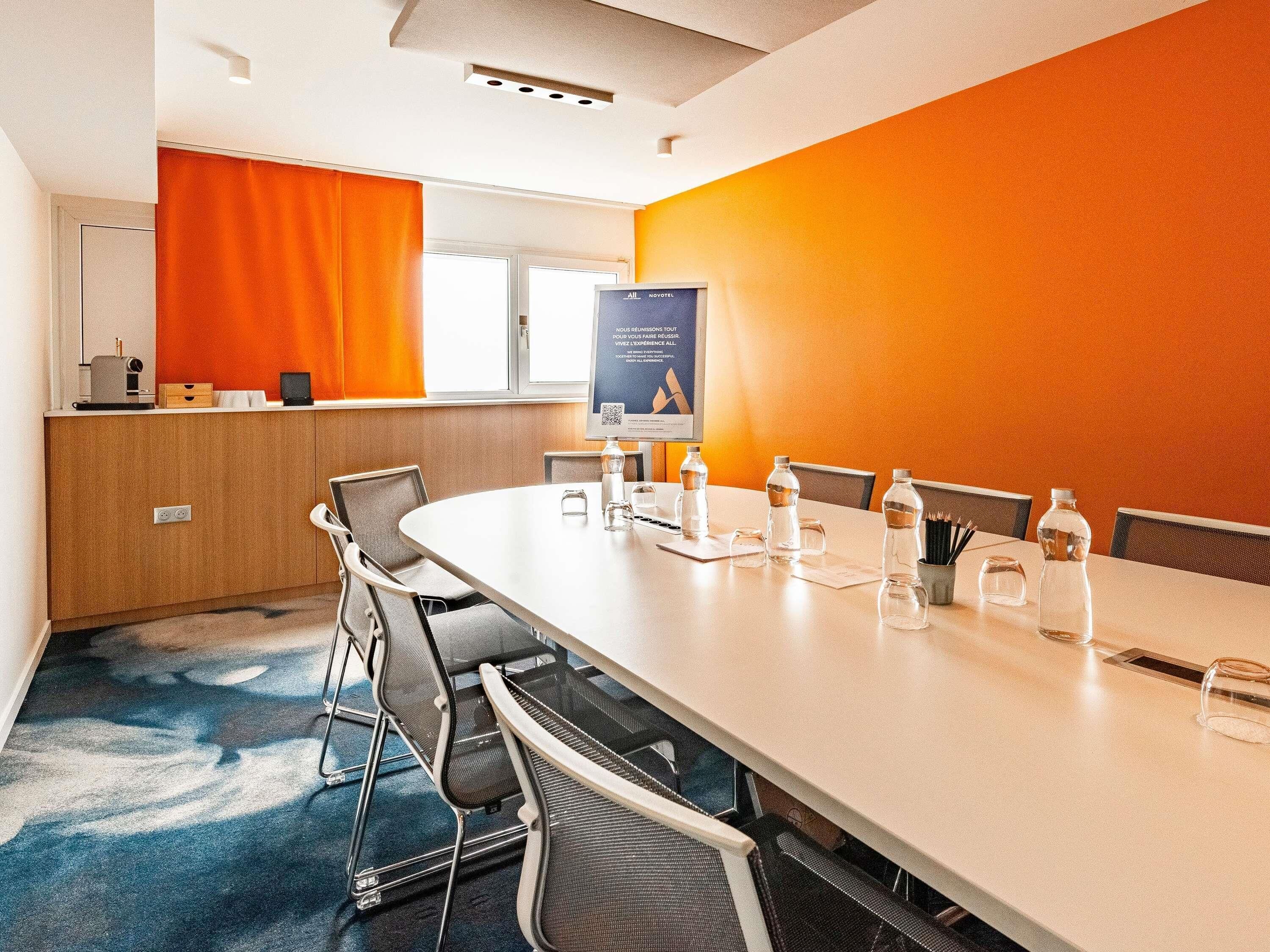 A conference room with a long table, chairs, a podium, and a poster on the wall.
