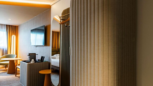 Una habitación de hotel moderna con televisor de pantalla plana, un escritorio con computadora portátil, un sofá cómodo y una cama.