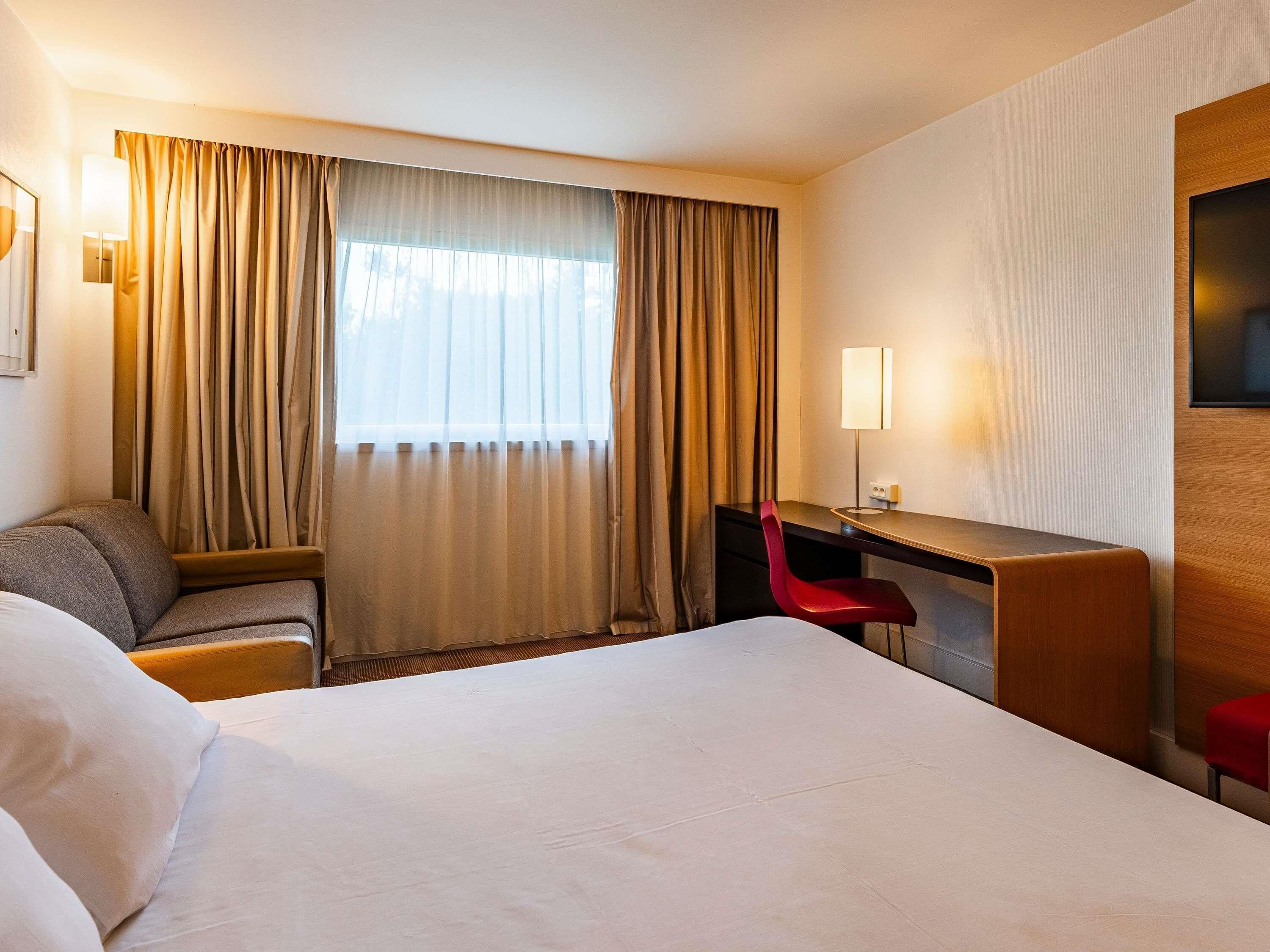 Ein Hotelzimmer mit Bett, Schreibtisch, Stuhl und Fernseher.