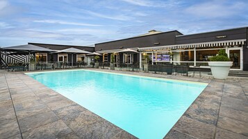 Una piscina al aire libre de temporada, sombrillas