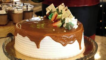 A cake with white frosting and chocolate drizzle on a glass plate.
