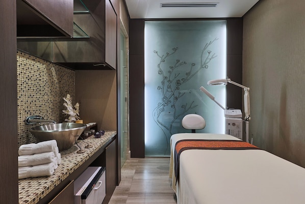 Un baño moderno con un espejo grande, un lavabo y una cama.