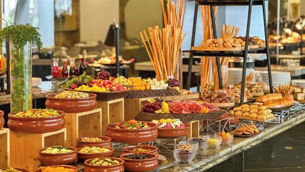 A buffet with various food items and a decorative plant.