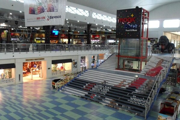 Un centro comercial de varios niveles con diversas tiendas, incluyendo un restaurante KFC y una sucursal de Banesco.