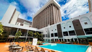 A hotel with a swimming pool, outdoor seating, and a modern architectural design.