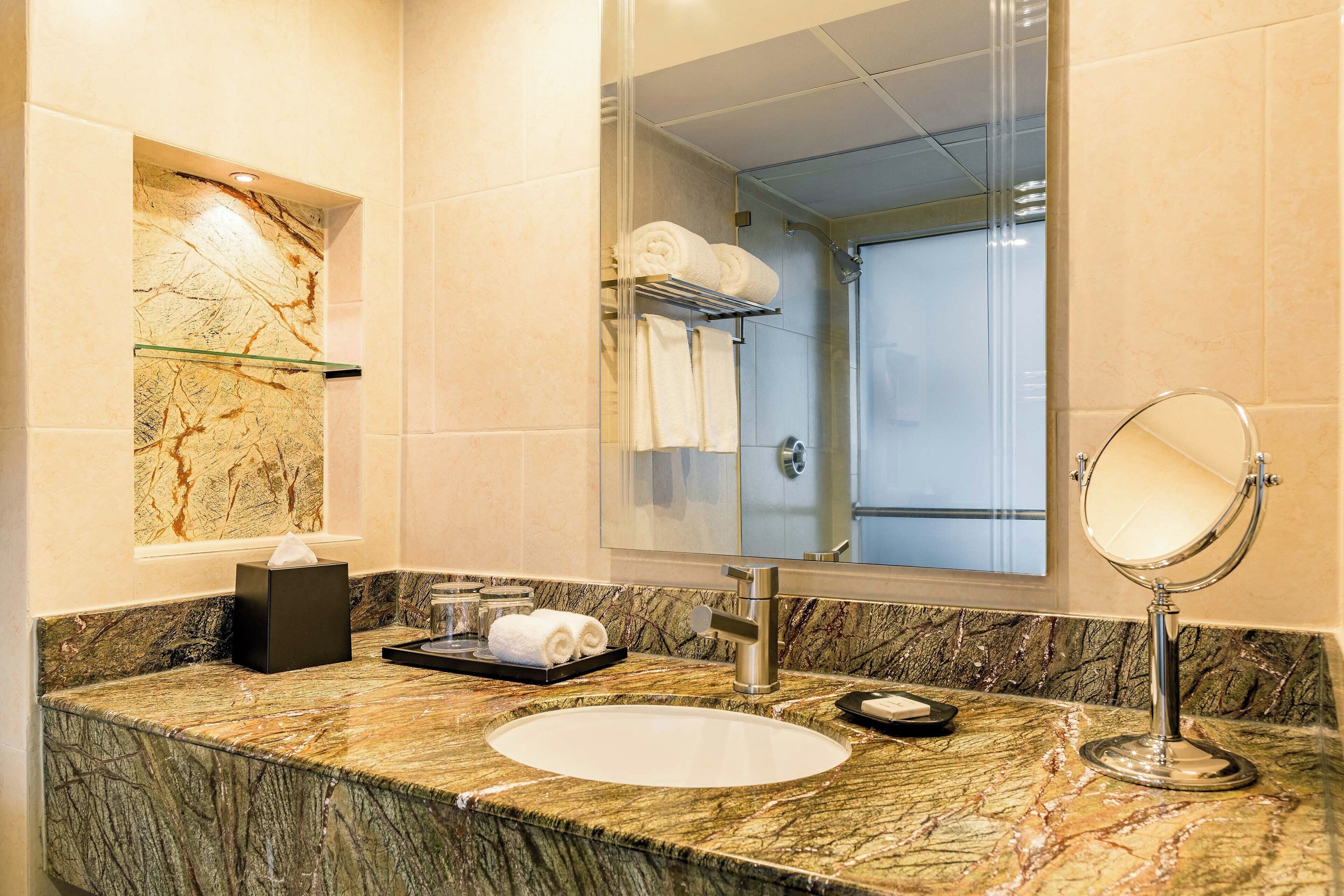 Une salle de bain avec un comptoir en marbre, un lavabo, un miroir et un porte-serviettes.