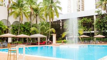 Una piscina al aire libre, sombrillas, sillones reclinables de piscina