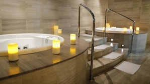 A spa area with a hot tub, candles, and a curved bench.