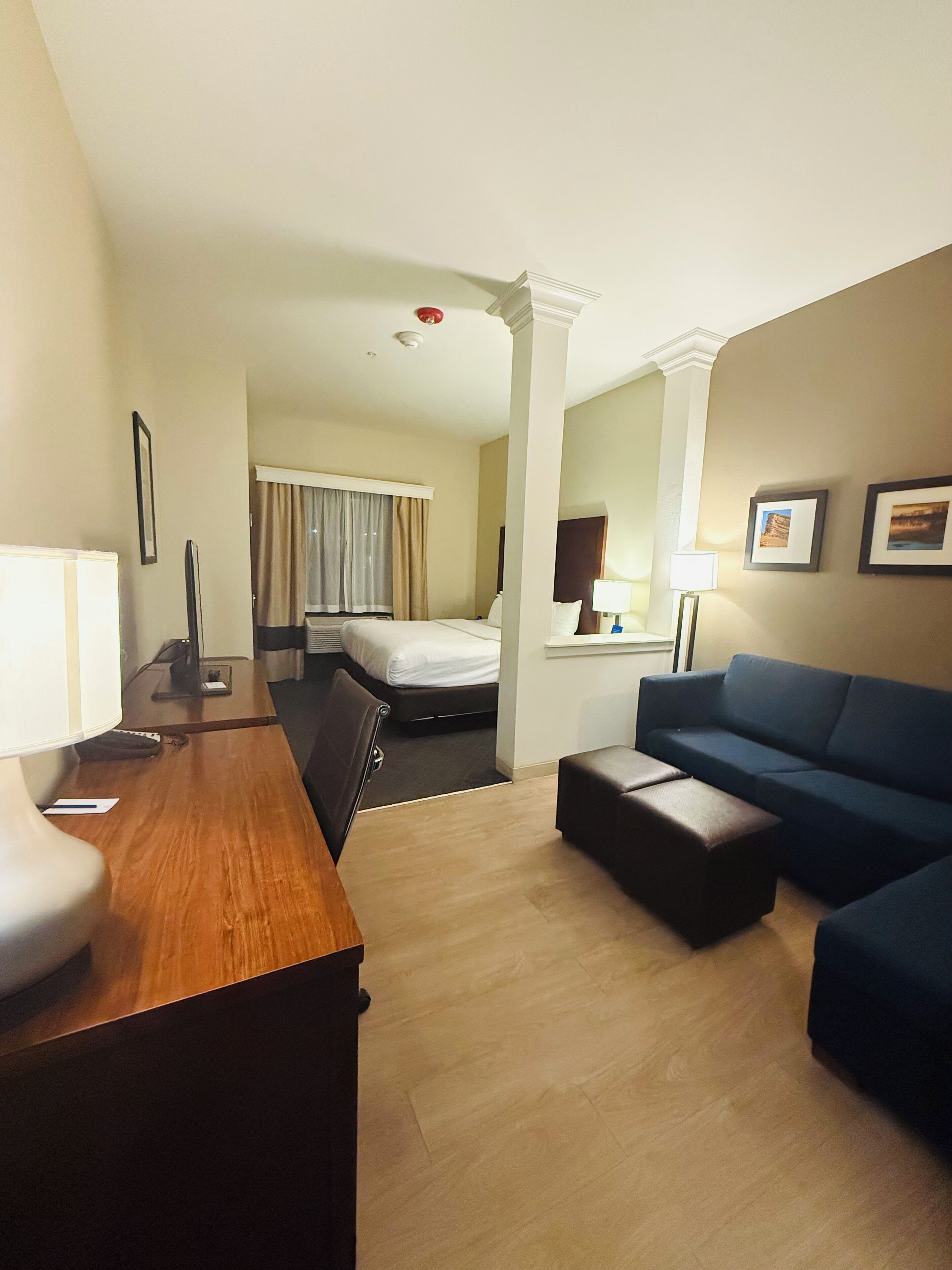Habitación de hotel con un escritorio de madera, un sofá azul, una cama y un espejo.