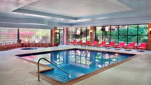 Una piscina interior con sillas reclinables rojas y una pared de ladrillo.