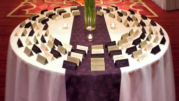 A round table with name cards and a floral centerpiece in a hotel lobby.