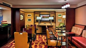 A hotel lobby with a dining area, a sofa, and a TV screen.
