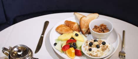 A breakfast setting with toast, fruit, yogurt, and coffee on a white table.
