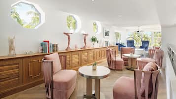 Un interior moderno con un mueble de madera, sillas tapizadas en rosa y una mesa redonda.