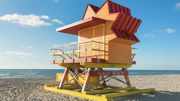 Una torre de salvavidas de diseño singular, ubicada en una playa de arena con el océano al fondo.