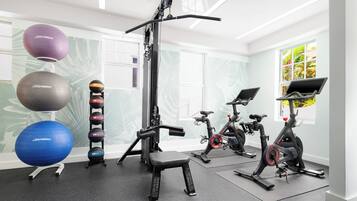 A gym with exercise equipment, including a squat rack, treadmills, and exercise balls.