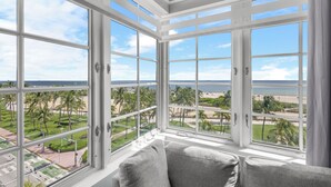 A room with large windows offering a view of a beach and palm trees. - Park Central South Beach (Miami Beach)