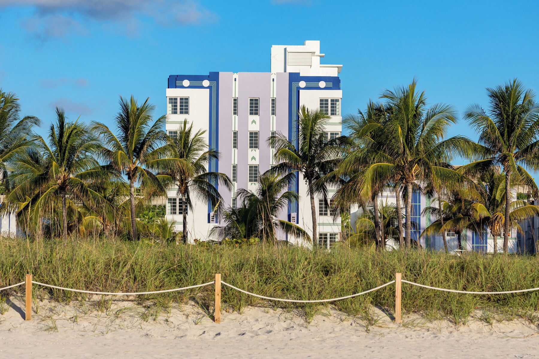 A beachfront hotel with a modern design, featuring multiple floors and a prominent blue and white color scheme.