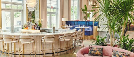 Un moderno vestíbulo de hotel con área de bar, asientos y grandes ventanales.
