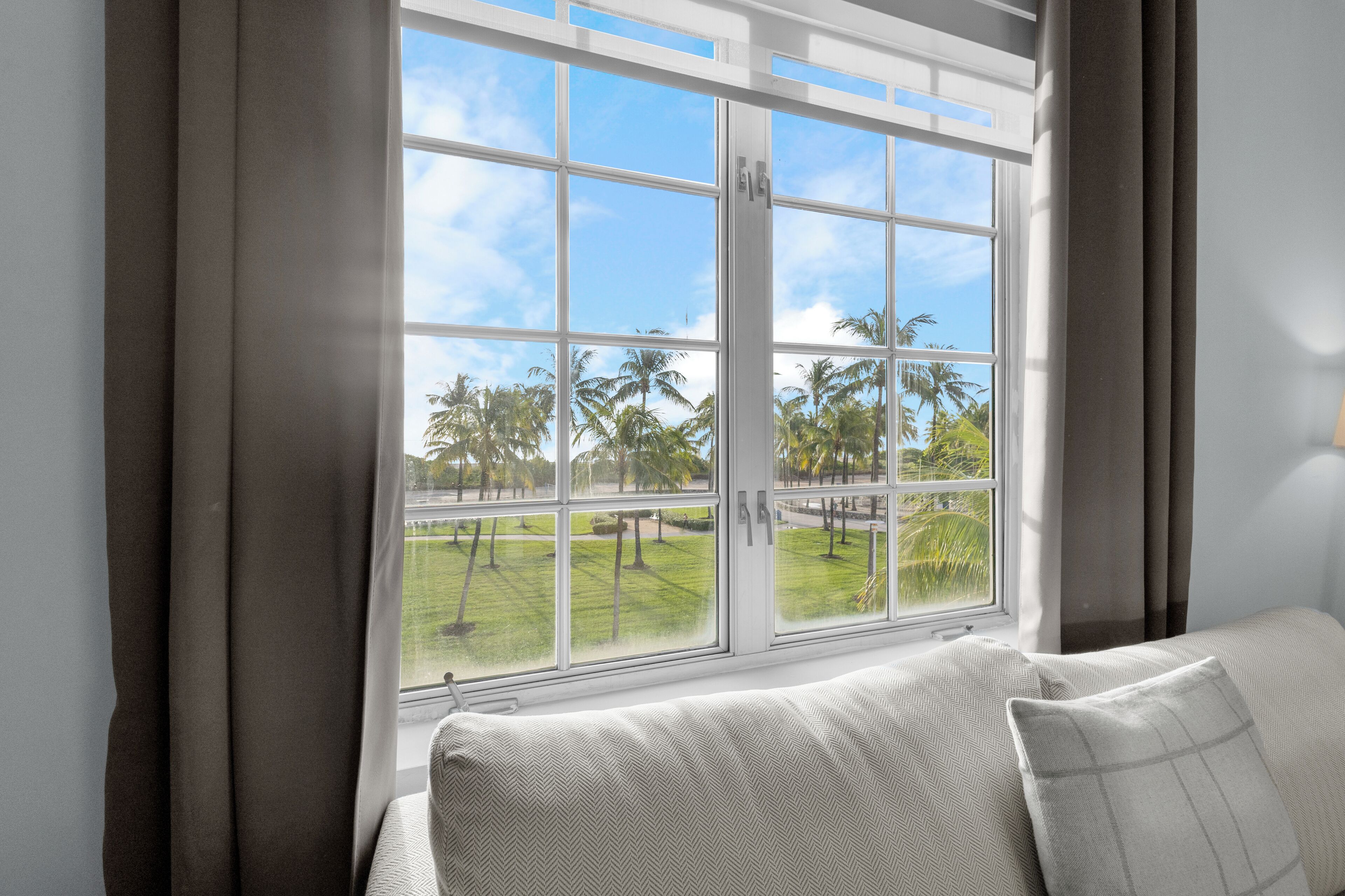 Una habitación con un ventanal grande, un sofá y cortinas.