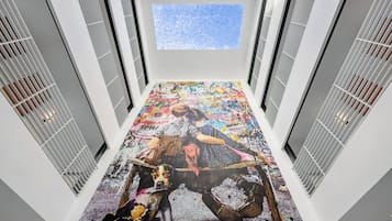 A modern interior with a large floor-to-ceiling mural, white walls, and a skylight.