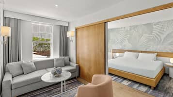 Una habitación de hotel moderna con una cama grande, un sofá, una mesita y vistas a zonas verdes.