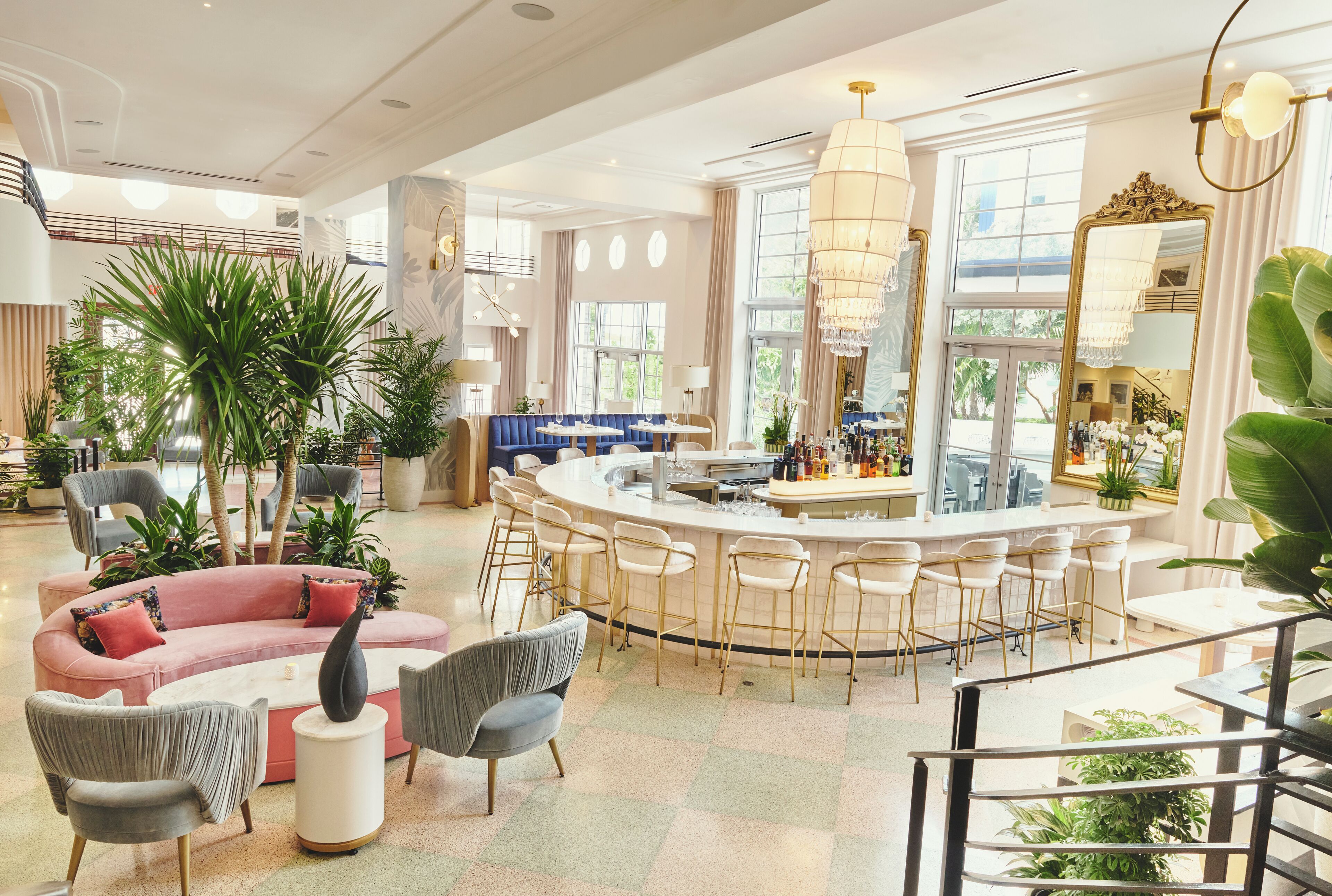 A spacious lounge area with a bar, seating arrangements, and large windows providing natural light.
