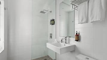 Un baño moderno con cabina de ducha de vidrio, un lavabo blanco y un espejo grande.