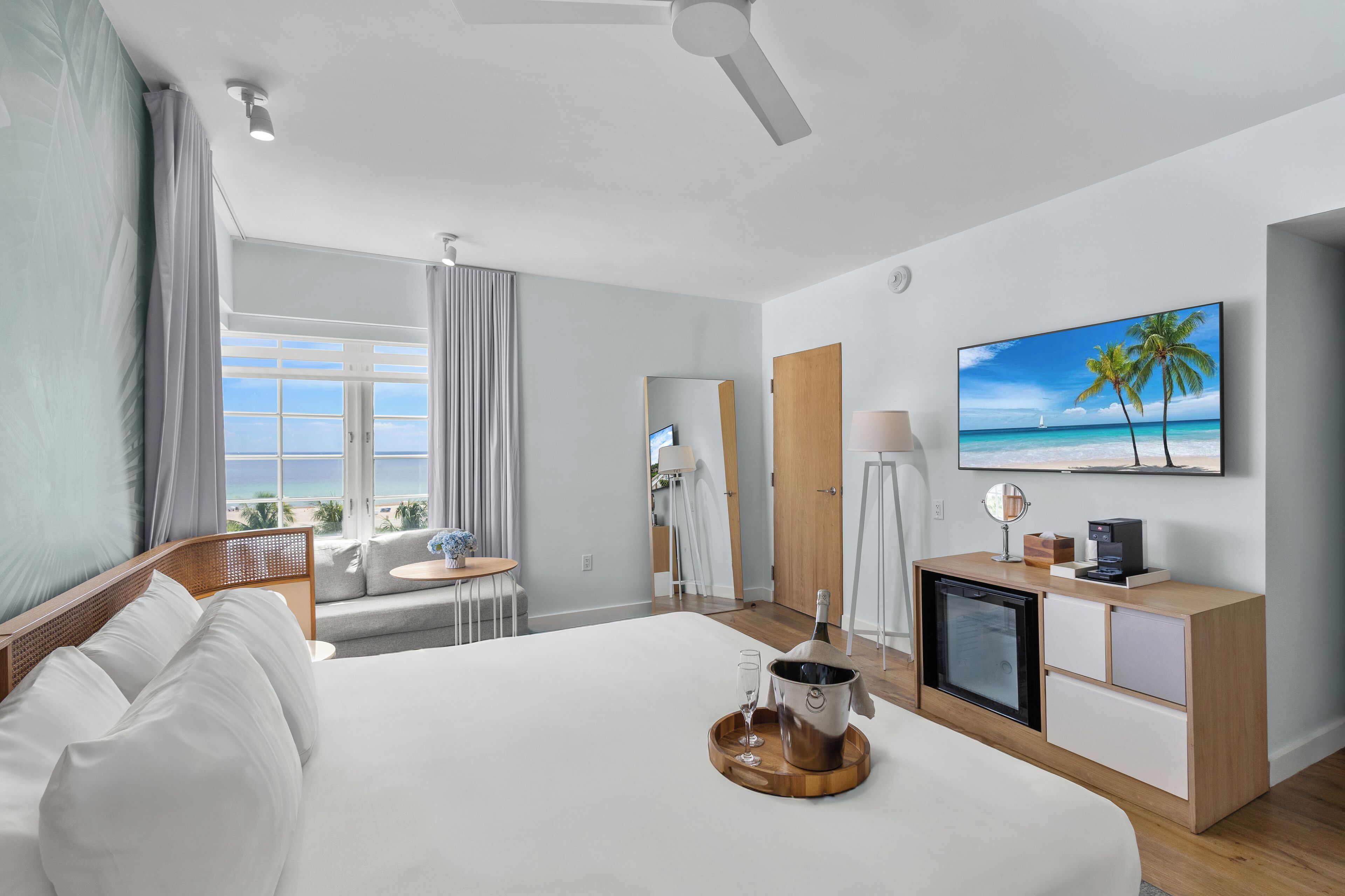 Une chambre d’hôtel équipée d’un lit, d’une télévision, d’un minibar, d’un bureau et offrant une vue sur l’océan.