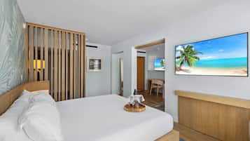 A hotel room with a bed, a wooden headboard, a painting of a beach, and a television on the wall.