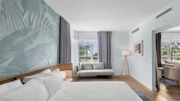 A hotel room with a large bed, a sofa, a small table, a lamp, and a view of the outdoors.