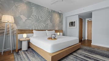 A modern hotel room with a large bed, a standing lamp, a wall-mounted artwork, and a ceiling fan.
