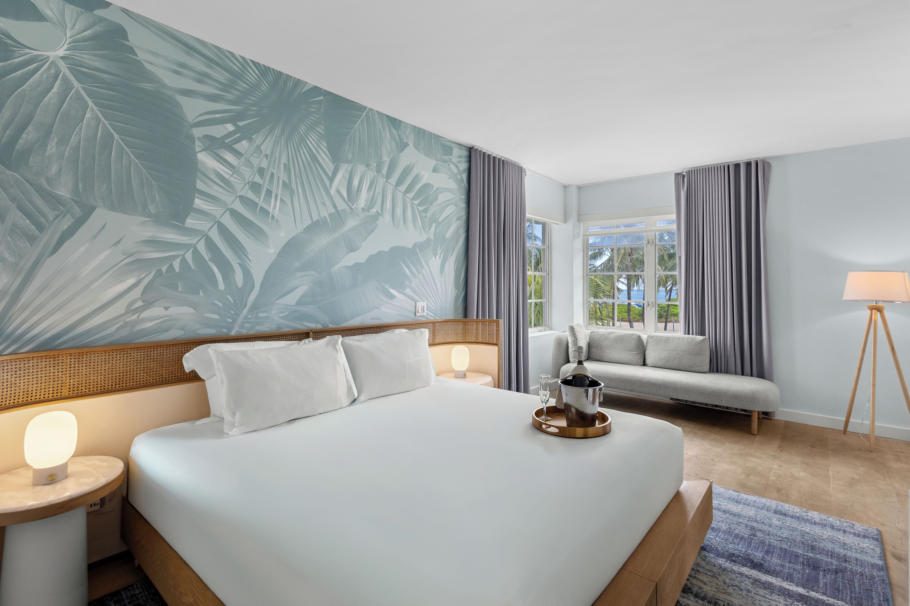 Une chambre d’hôtel avec un grand lit, un canapé, une lampe et une vue sur l’extérieur.
