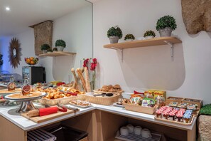 Un bufé de desayuno con diversas opciones de comida, como pasteles, frutas y bebidas.