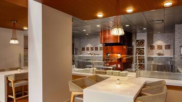 Un intérieur de restaurant moderne avec un espace de restauration central, un plafond en bois et des luminaires suspendus.