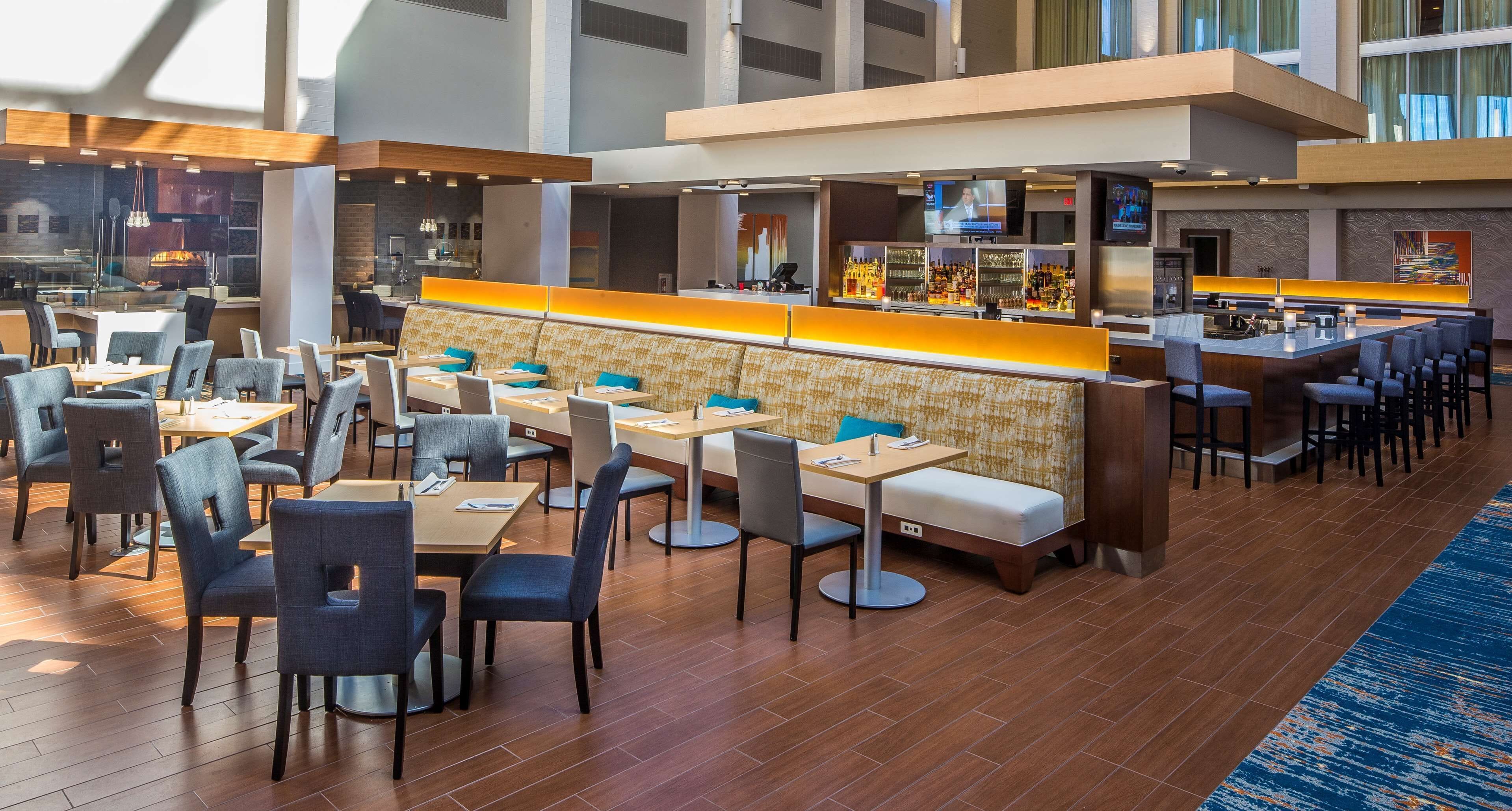 Un moderno vestíbulo de hotel con zona de bar, espacios de estar y vistas a la ciudad.