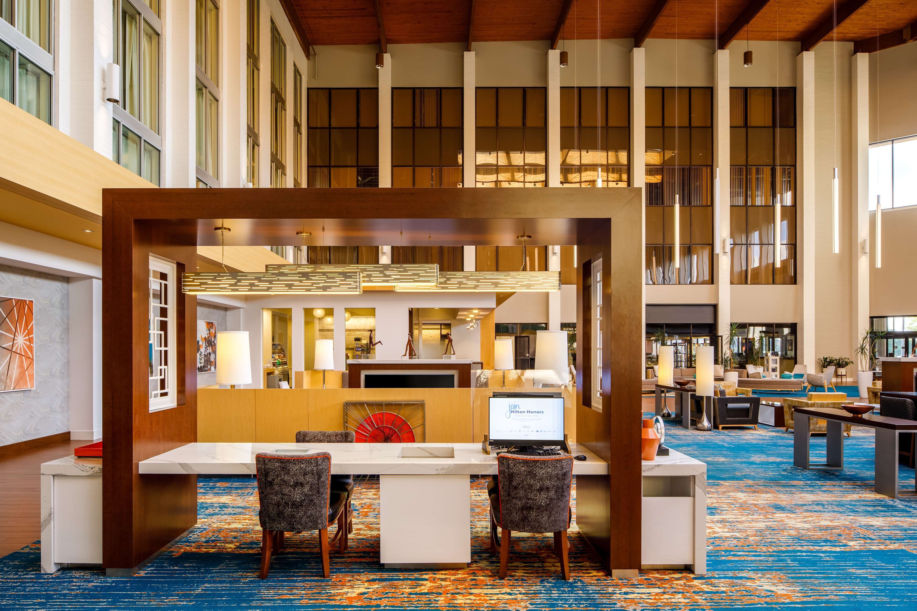 A spacious lobby with a reception desk, seating area, and large windows.
