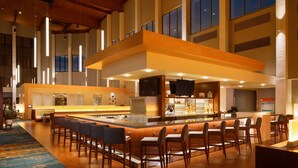A spacious bar area with multiple seating options and a central island, featuring a modern design with wooden accents and large windows. - DoubleTree by Hilton Pittsburgh - Cranberry (Mars)