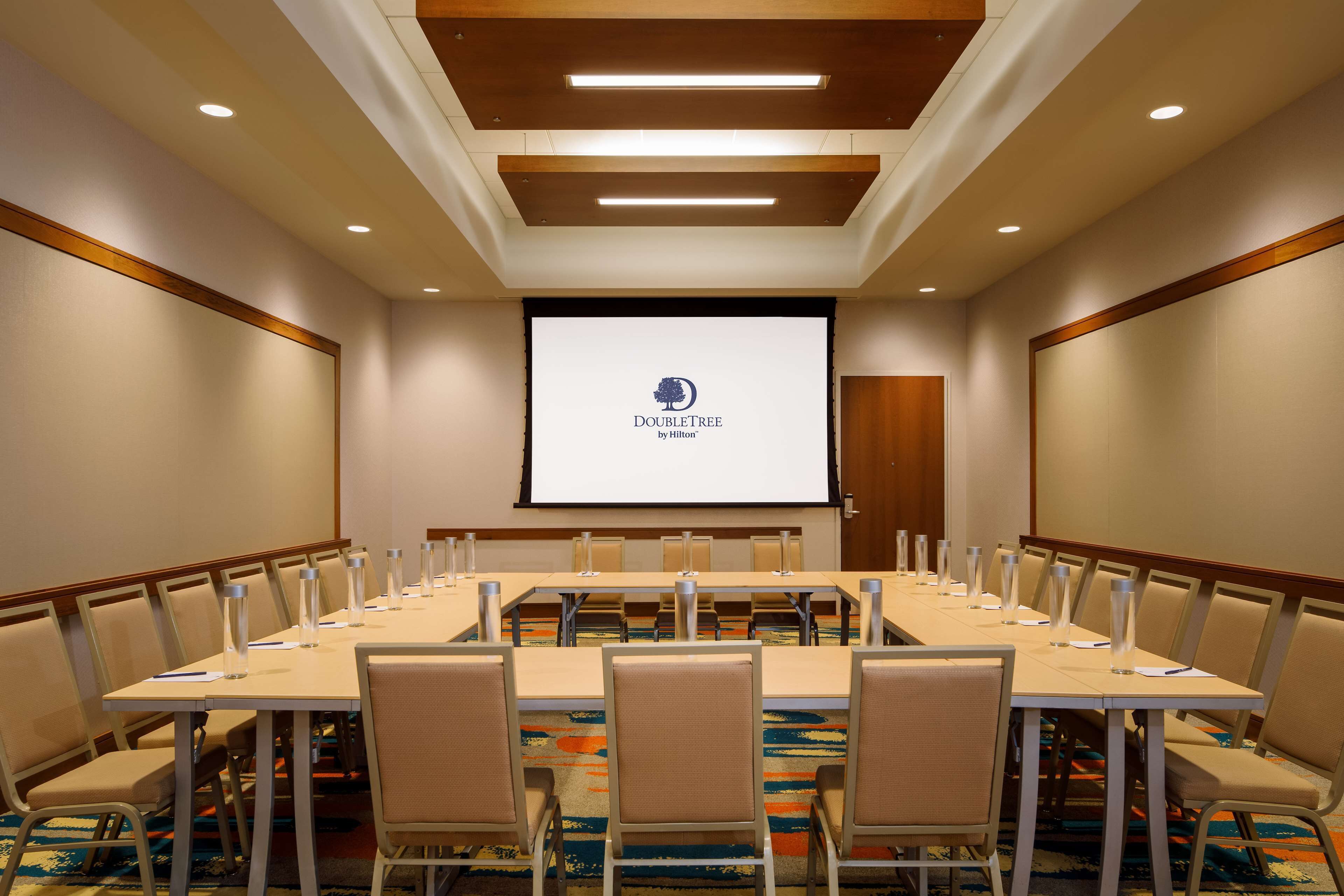 A conference room with a long table, chairs, and a projector screen displaying the DoubleTree by Hilton logo.