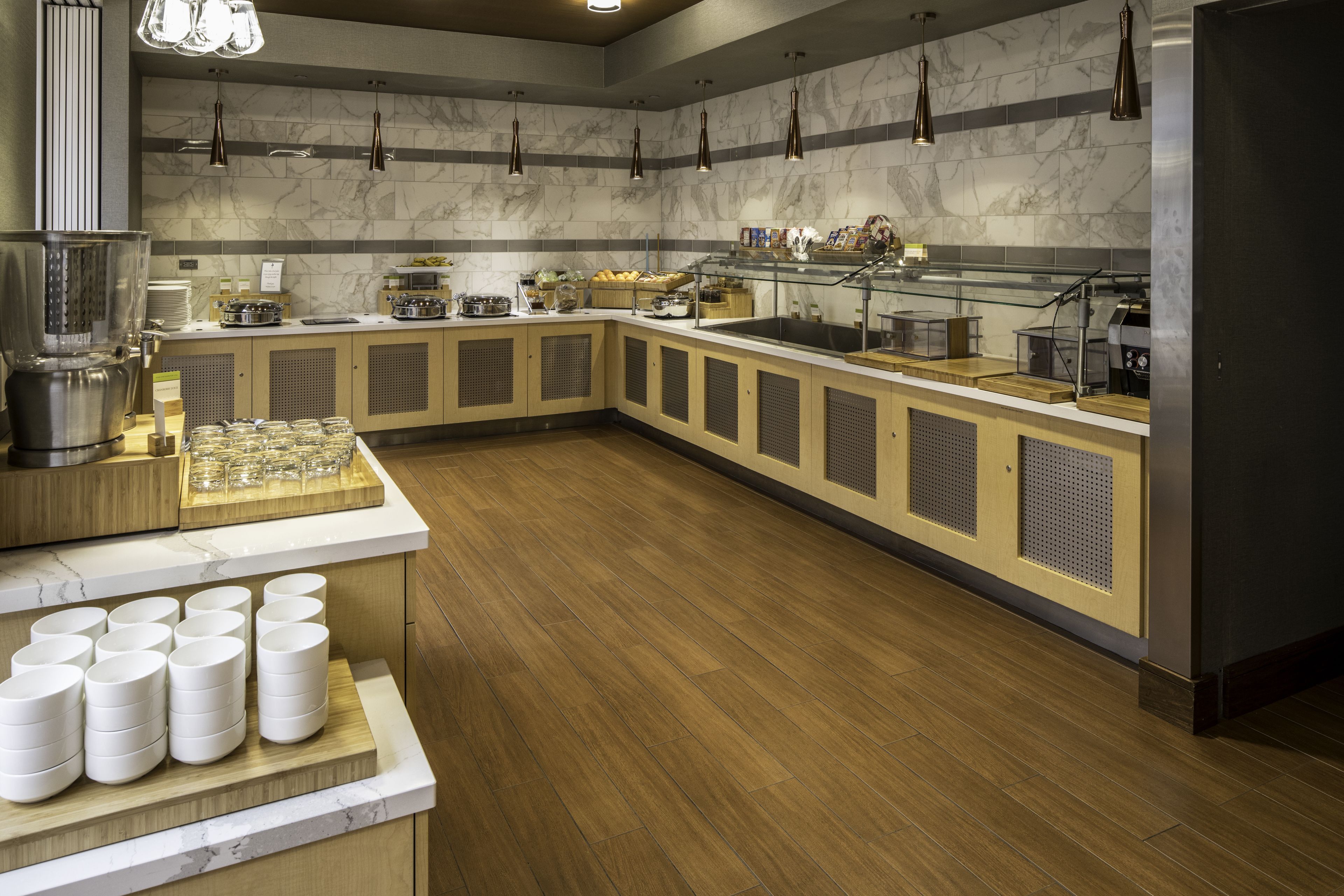 Une cuisine moderne dotée de plans de travail en marbre, d’armoires en bois et de divers appareils de cuisson.