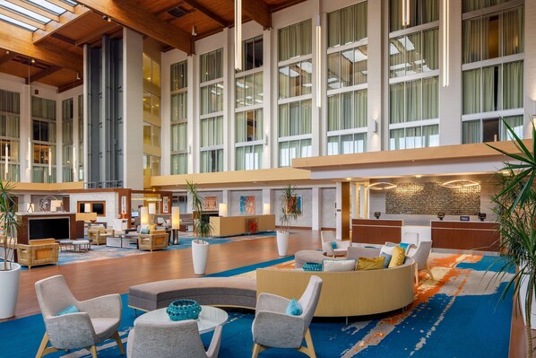 A spacious lobby with high ceilings, large windows, and a variety of seating arrangements including sofas and chairs.