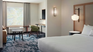 A hotel room with a bed, a desk, a chair, a lamp, and a large window with curtains. - Fairfield by Marriott Inn & Suites Matteson Chicago (Matteson)